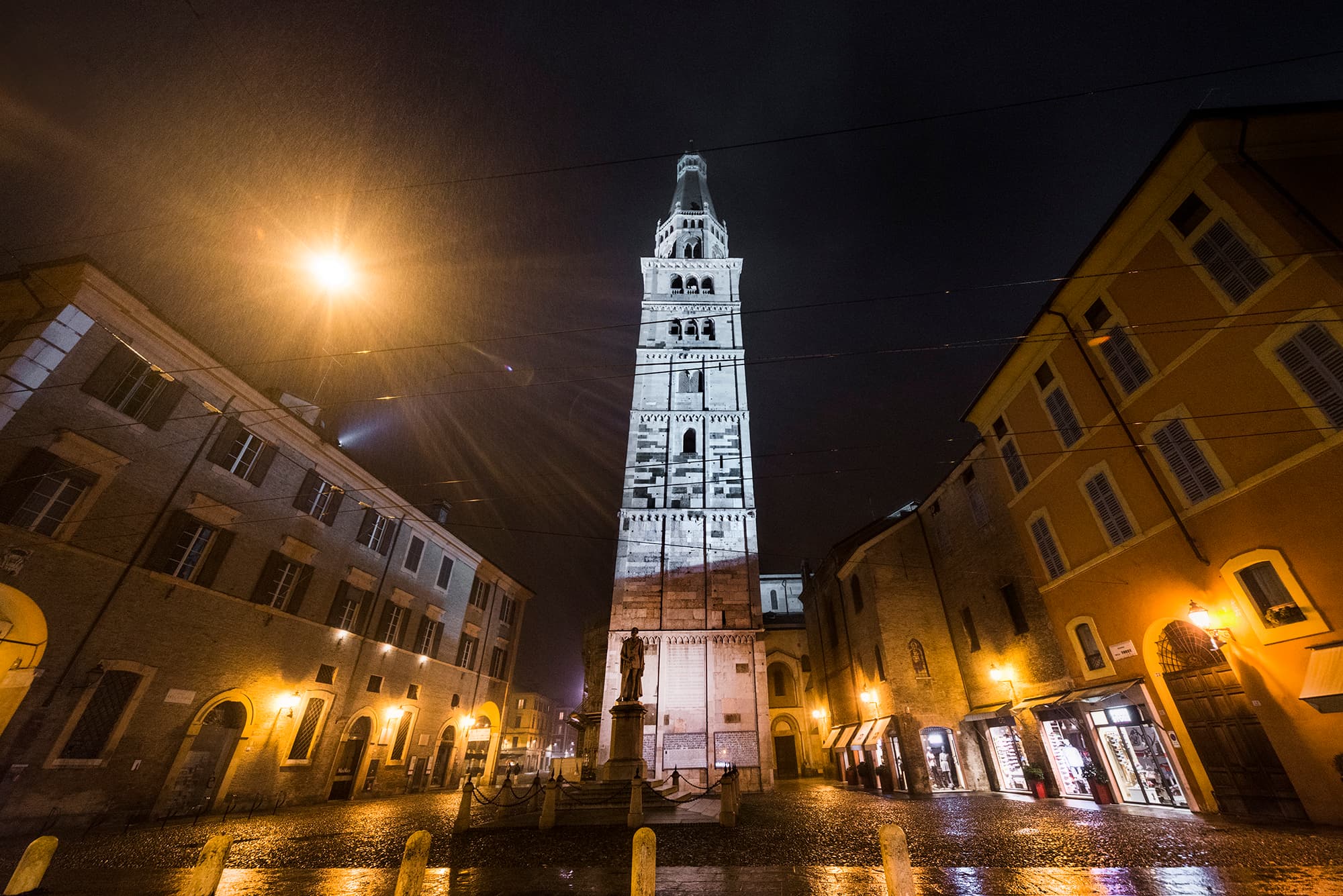 La Ghirlandina illuminata di notte sulla piazza bagnata, in inverno